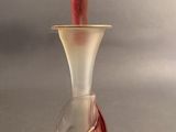 un vase en verre avec une anse rouge posé sur une table