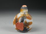 an orange and white glass snuff bottle sitting on top of a table