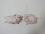 two pig figurines sitting on a white surface