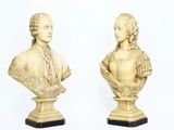 une paire de bustes sculptés représentant un homme et une femme, posés sur des socles en marbre