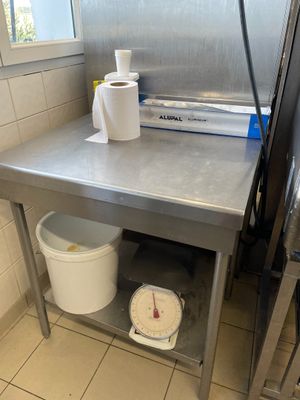 table de travail en acier inoxydable sur laquelle se trouvent deux seaux et deux rouleaux de papier toilette