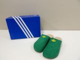 green slippers with a box of adidas on a white table