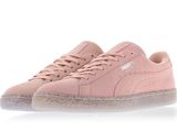 Les baskets Puma Sued sont rose pâle et ont des semelles transparentes.