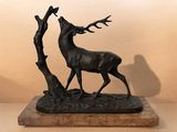 statue d'un cerf aux bois accrochés à un arbre, posée sur un socle en marbre