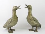 pair of bronze ducks on feet with open beaks on a white background