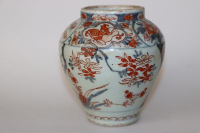 un vase bleu et blanc orné de fleurs rouges