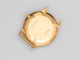a close up of a gold watch on a gray surface