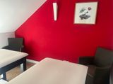 a bed and a chair in a room with a red wall