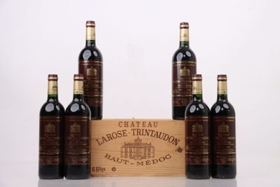 quatre bouteilles de vin sont alignées devant une caisse en bois