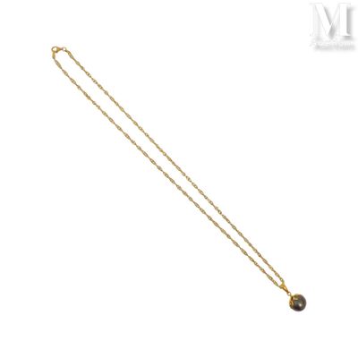 un collier en or orné d'une pierre noire sur fond blanc