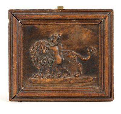 une plaque en bronze représentant un lion et une femme sur un rocher