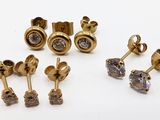 trois paires de boucles d'oreilles en or et diamants posées sur un fond blanc