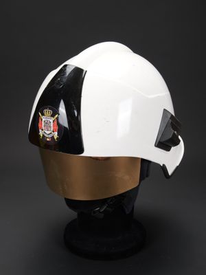 casque blanc et doré posé sur un socle noir, sur fond noir