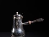 a silver coffee pot with a wooden handle on a black surface