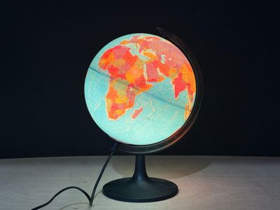 un petit globe lumineux posé sur un socle, sur une table