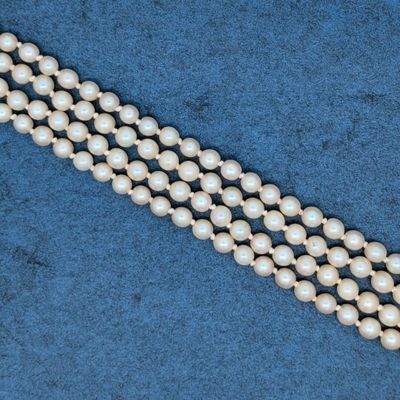 un gros plan sur trois rangs de perles sur fond bleu