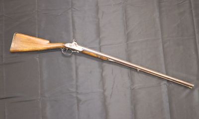 an old rifle with a wooden handle on a black background