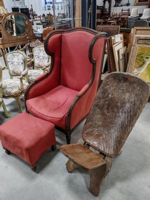 un fauteuil rouge et un pouf dans une pièce remplie de meubles anciens
