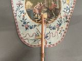 a small fan with a painting on it on a stand