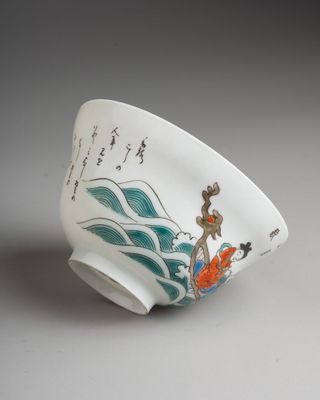 a white bowl with a painting on it sitting on a table