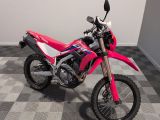 une photo d'une moto tout-terrain rose garée sur un sol à damier