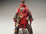 statue d'un homme assis sur un rocher, avec un cordon rouge autour du cou