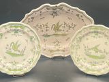 three green and white plates with birds on them sitting on a table
