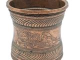 an old copper cup with a design on the side