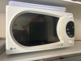a white microwave sitting on a shelf in a kitchen