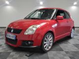 the red suzuki swift is parked in a room with a checkered floor