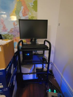 a computer on a cart in a room with boxes and a map on the wall