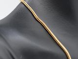 a close up of a mannequin torso wearing a gold chain necklace