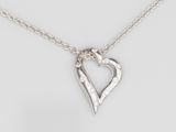 un collier composé d'un cœur en argent serti de diamants, monté sur une chaîne