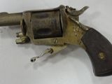 un petit revolver avec une crosse en bois posé sur une surface blanche