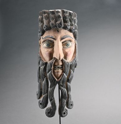 une image représentant un masque muni d'une barbe, posé sur un socle
