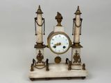 a white marble clock on a stand with chains around it