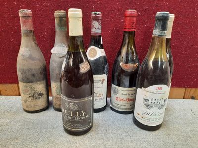 Plusieurs bouteilles de vin sont alignées sur une table devant un mur rouge
