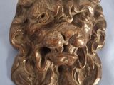 une tête de lion en bronze sur un fond blanc