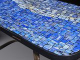 a close up of a blue mosaic table with metal legs