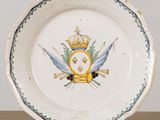 a white plate with a gold crown and two swords on it