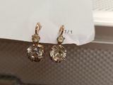 pair of gold tone crystal earrings hanging from a window sill