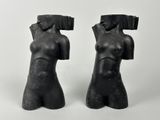 pair of black sculptures of female torsos on a white background