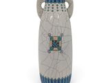 un vase blanc orné d'un motif bleu et vert