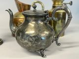 a silver tea pot sitting next to other silver and gold teapots