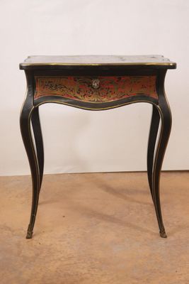 une table noire et dorée surmontée d'un tiroir