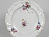une assiette blanche décorée de fleurs, posée sur un socle