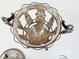 a silver bowl sitting on top of a table next to a silver plate