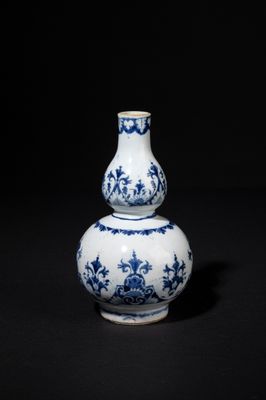 blue and white vase on a black surface with a black background
