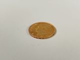 a gold coin sitting on a white surface