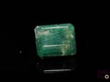 a close up of a green emerald stone on a black surface